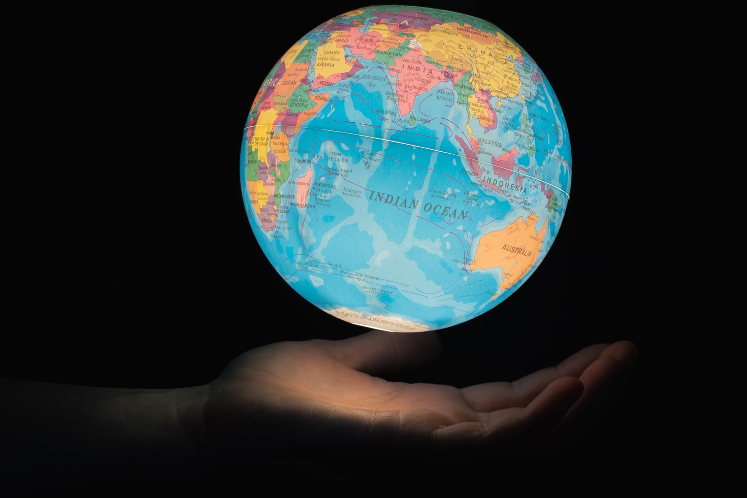 Black background with hand holding a floating globe of the earth representing crypto around the world